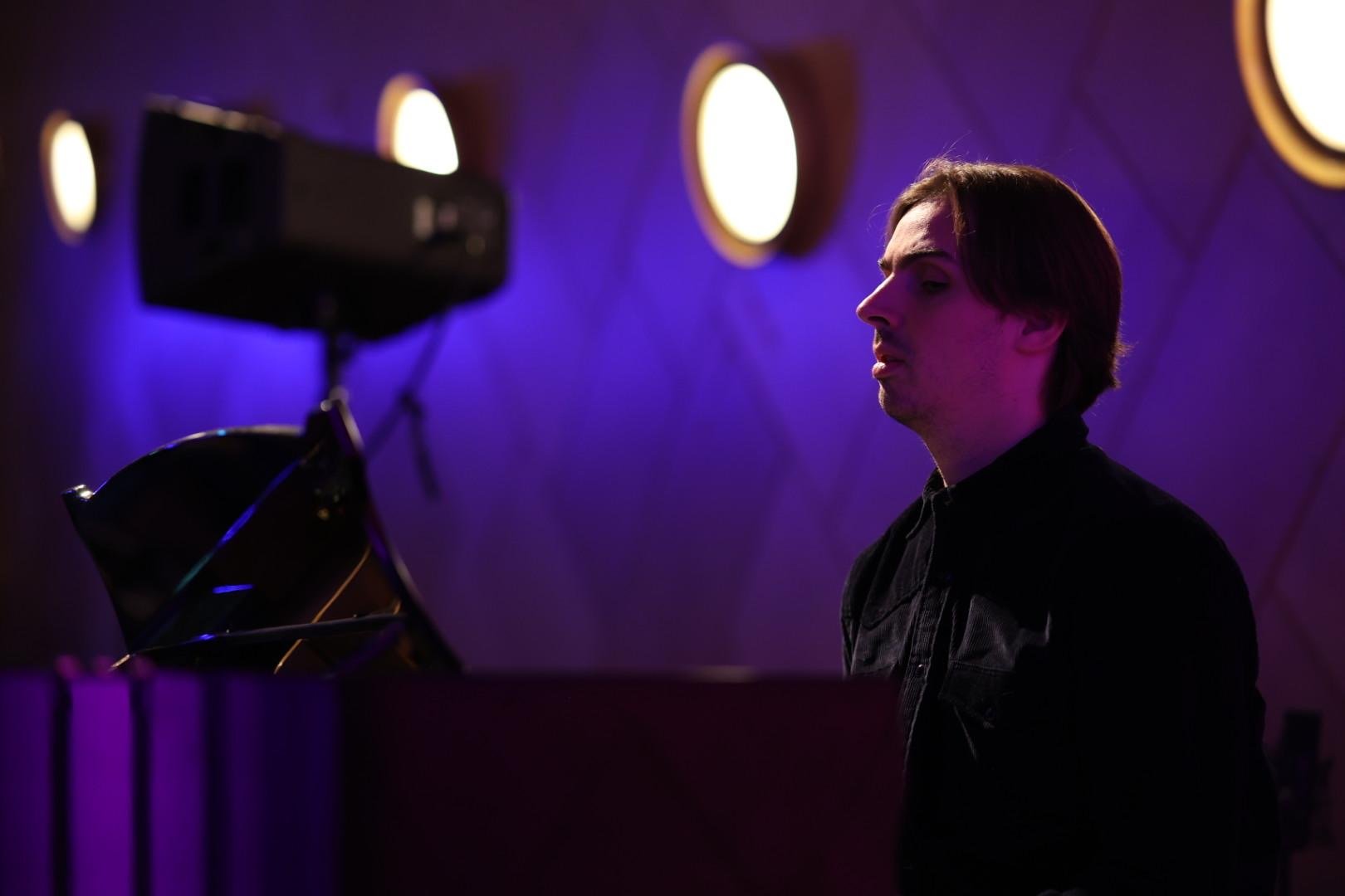 Thomas Tvedt ved flygelet i Store Studio, i dempet scenelys.