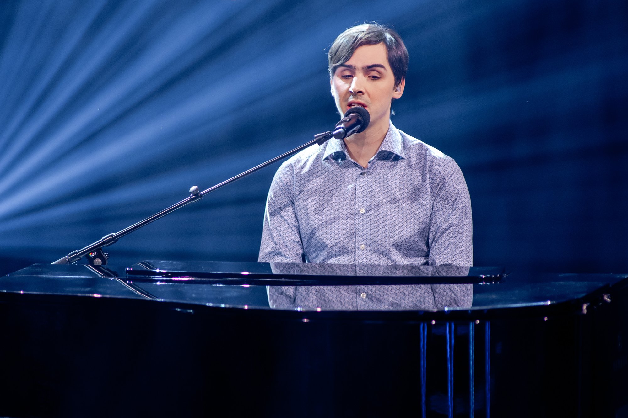Thomas Tvedt ved flygelet i The Voice, syngende i mikrofon.