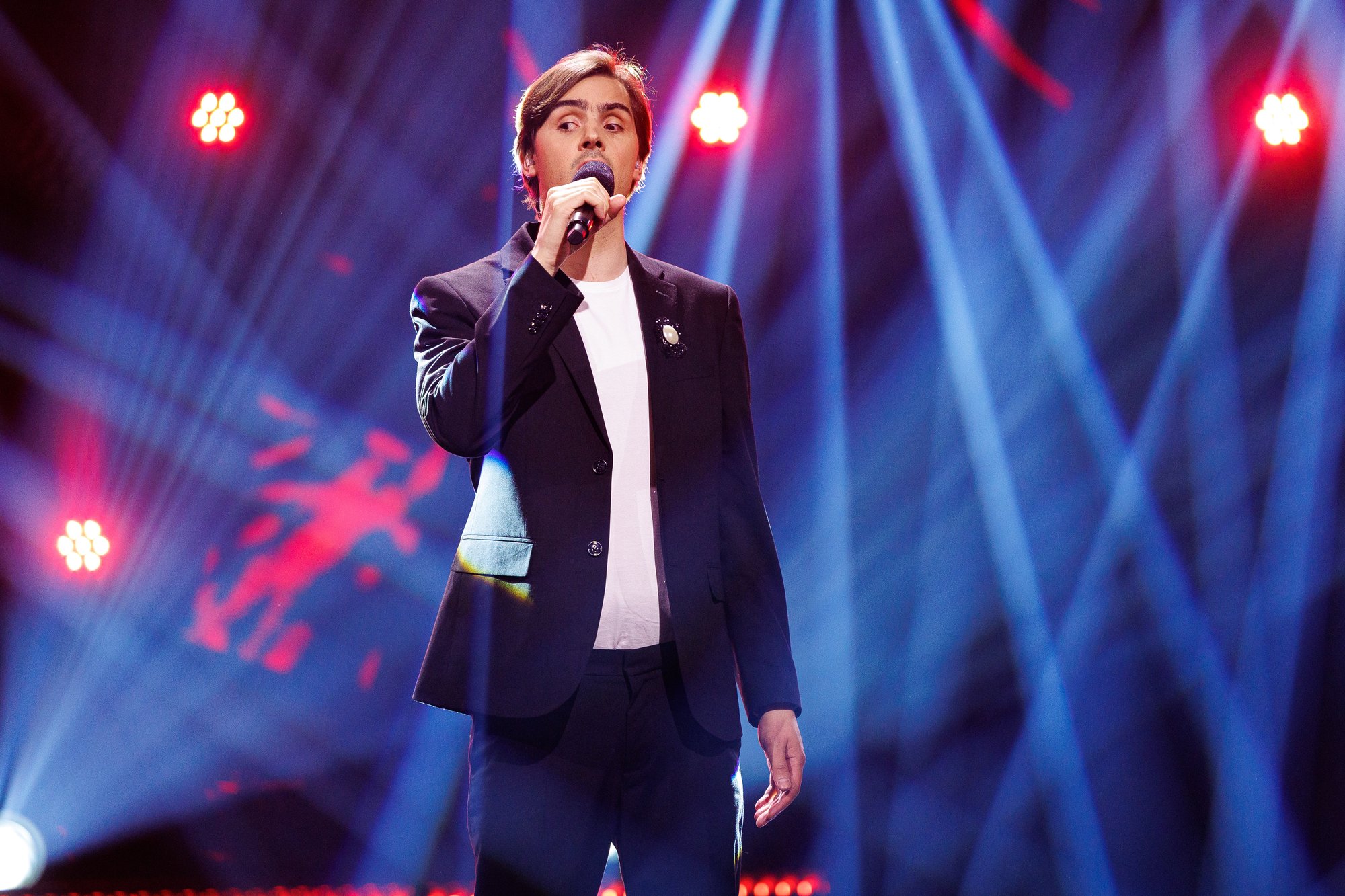 Thomas Tvedt på scenen i The Voice, syngende med håndholdt mikrofon.